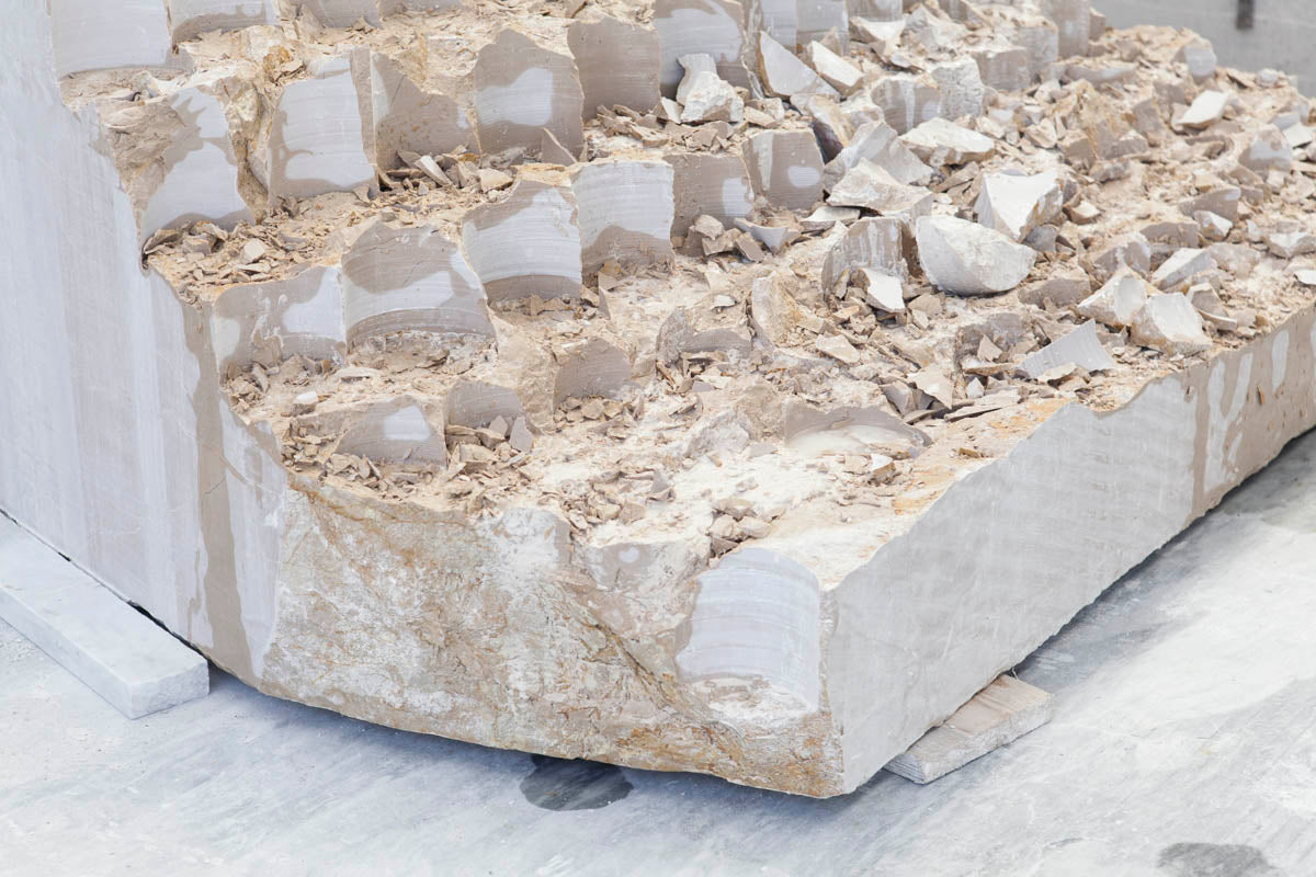 Rough-hewn marble block in a Carrara workshop, bespoke marble objects made in Italy
